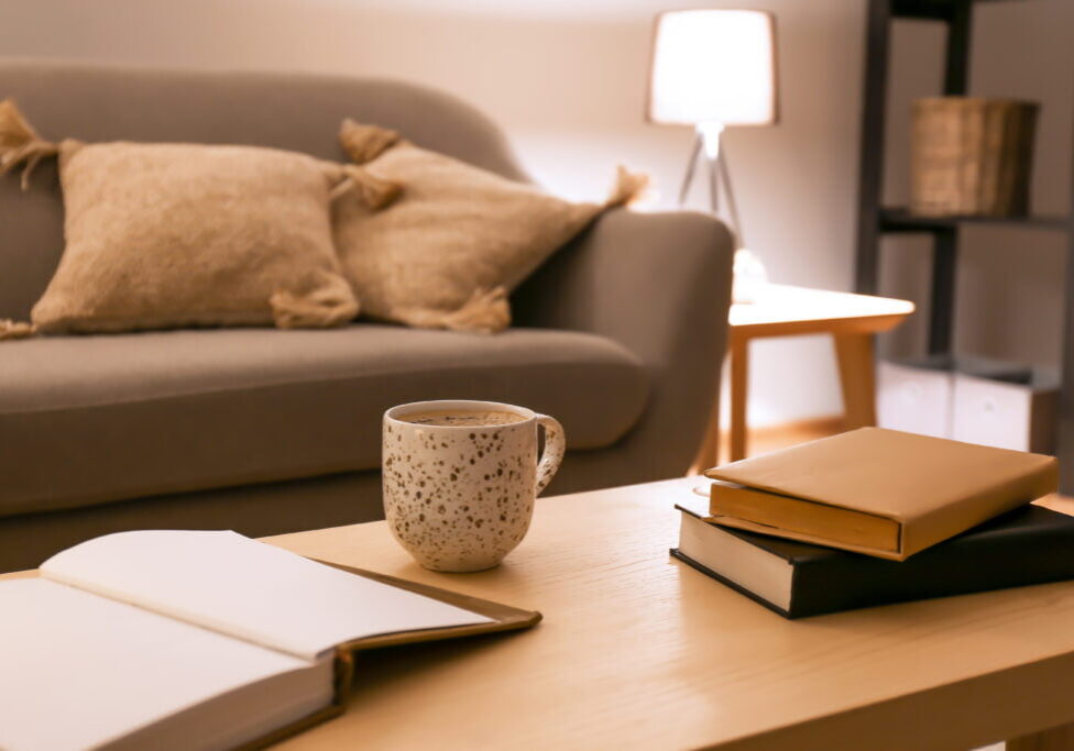 Books with cup of coffee on table in room at night